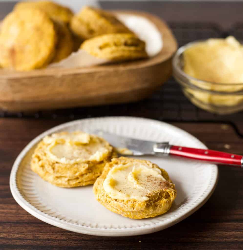 Plate with a sliced Bisquick Pumpkin Biscuit, topped with honey butter.