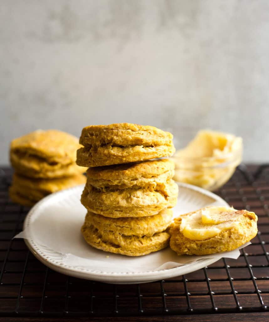 A stack of pumpkin biscuits with a bowl of honey butter.