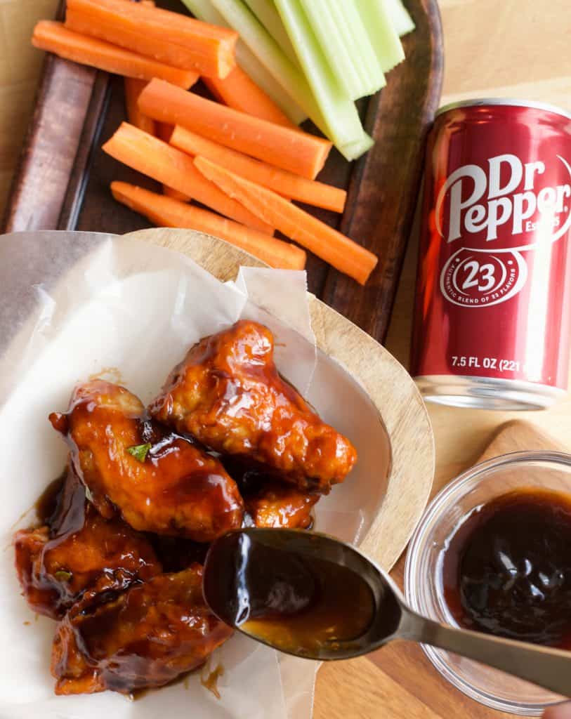 spooning Dr Pepper hot sauce on air fryer cooked chicken wings