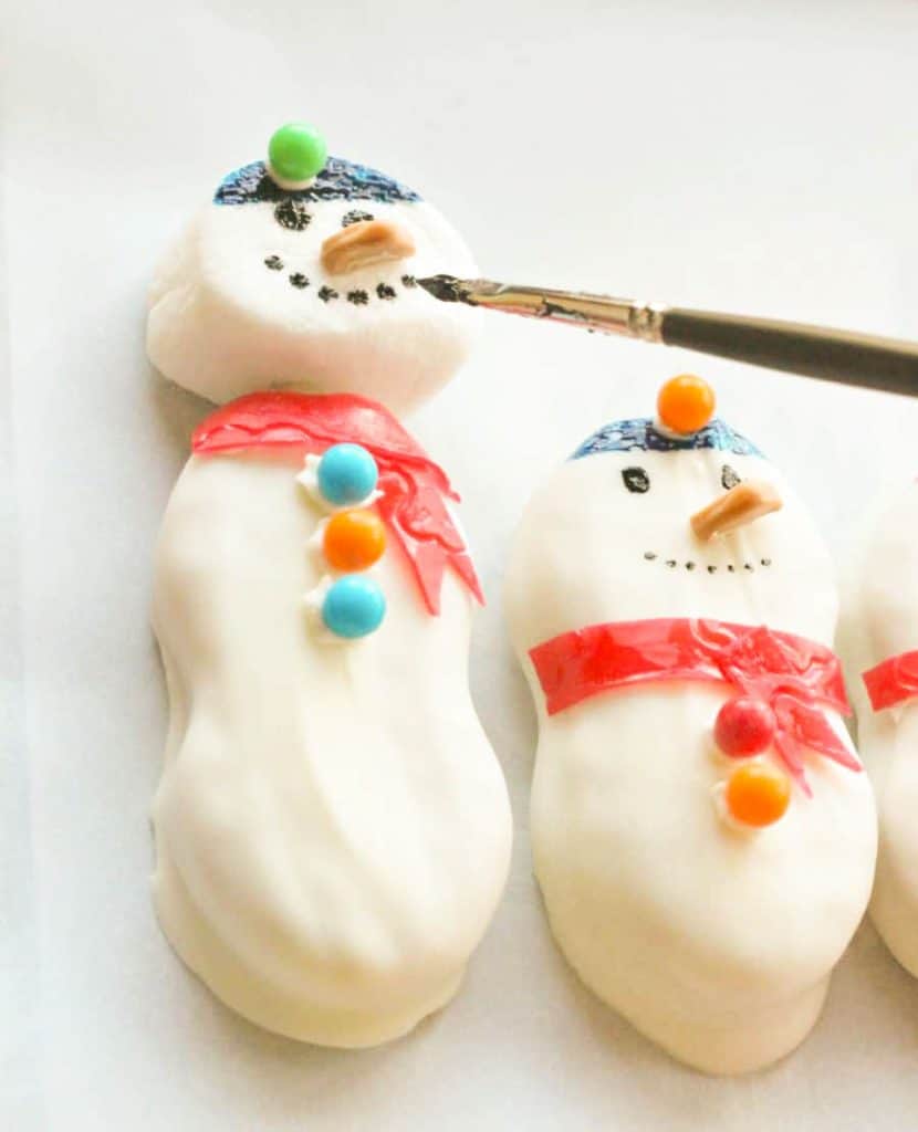 nutter butter snowmen cookies being decorated