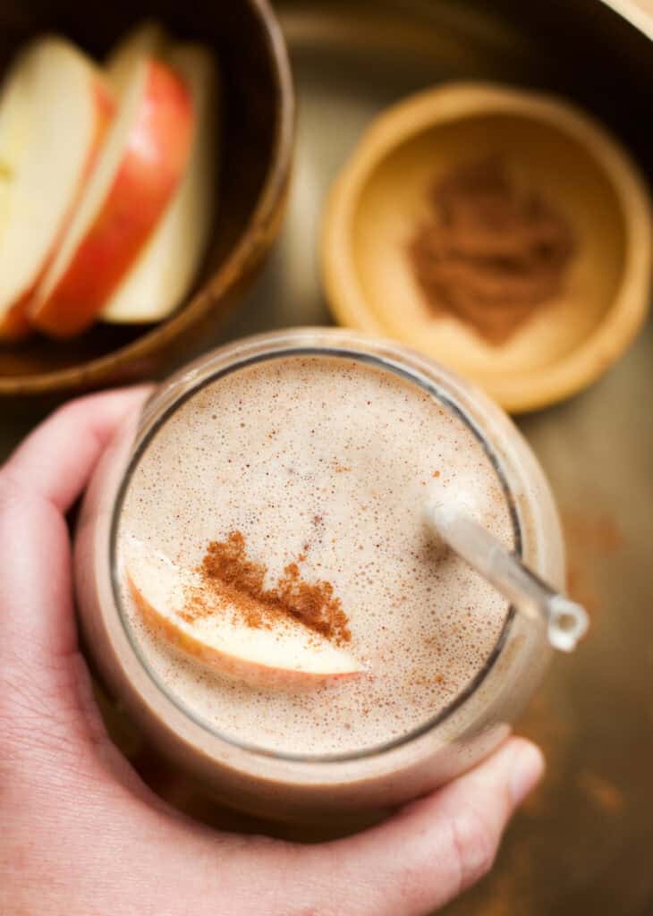 Hand holding an apple pie smoothie made with Greek yogurt and oats.