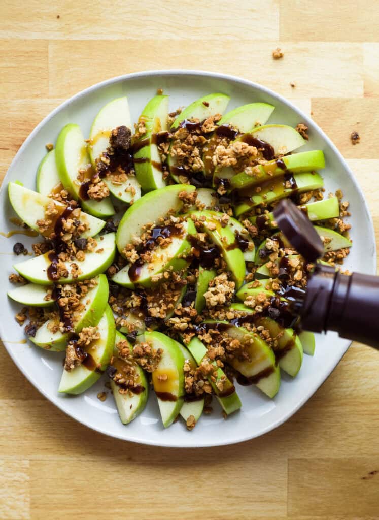 drizzling chocolate syrup onto loaded apple nachos