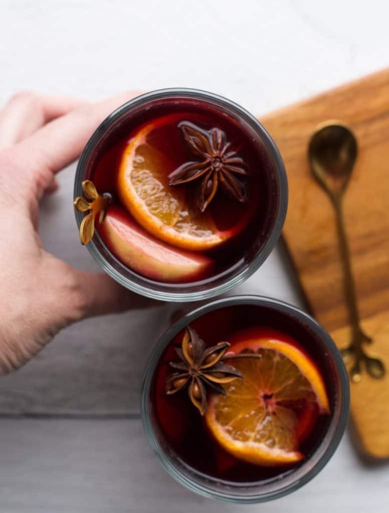 hand holding glass of mulled wine and spices