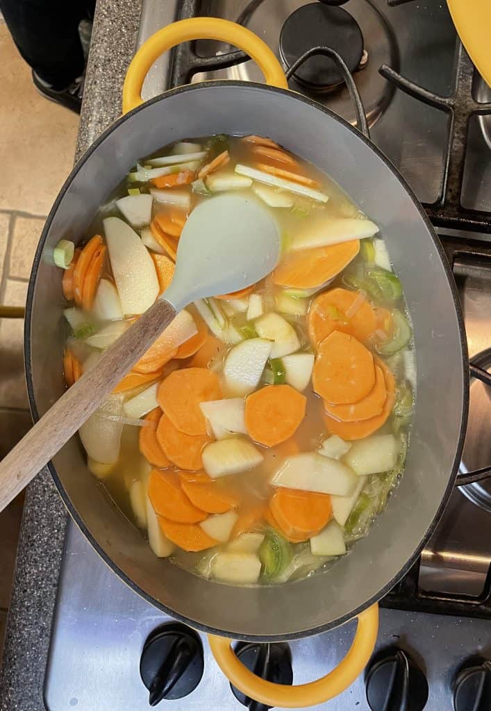 slices of sweet potato and apple cooking in a soup pot