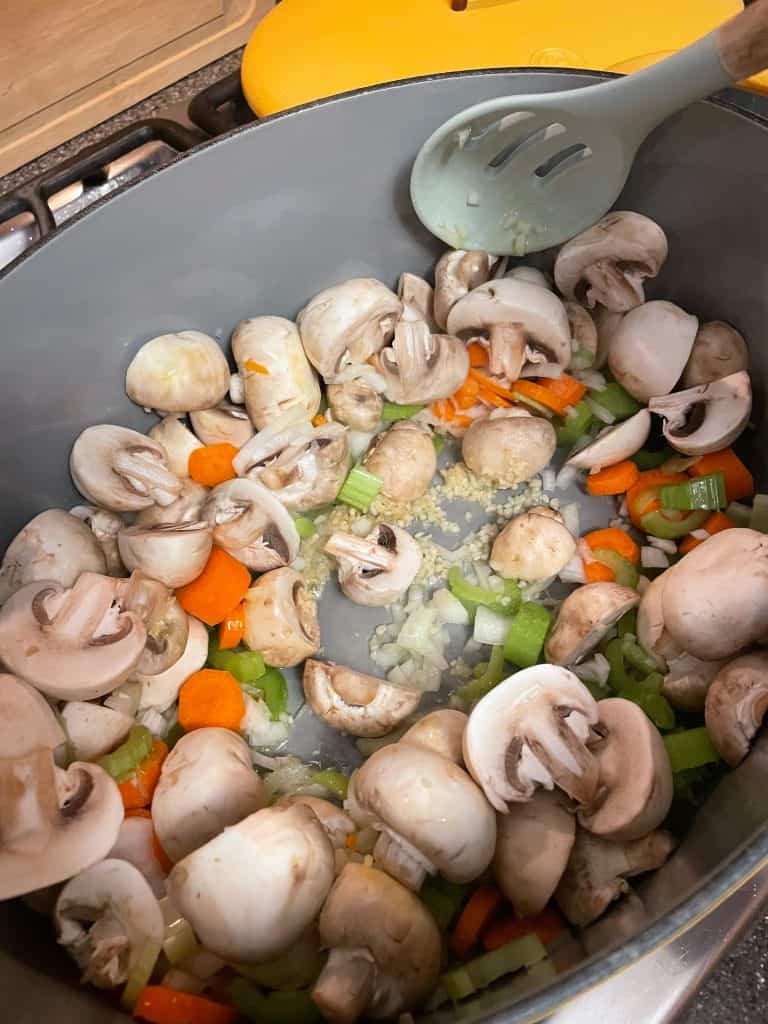 mushrooms and vegetables sautéing in a soup pan
