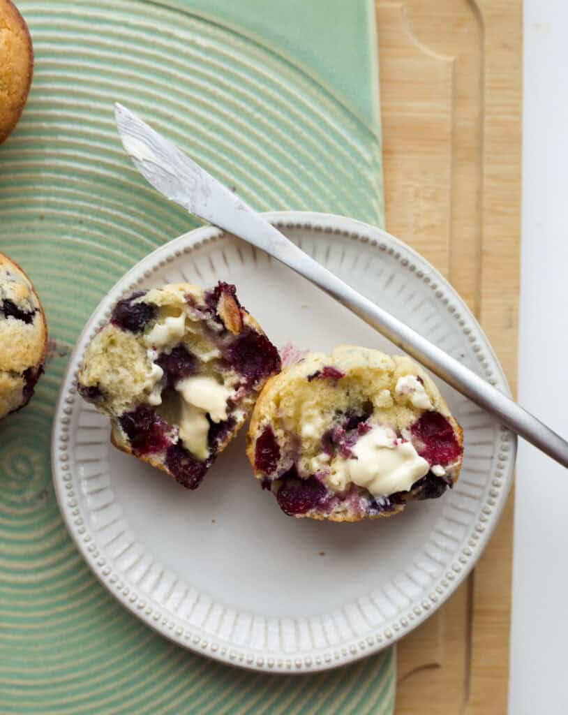 Freshly baked blueberry muffin, sliced in half and buttered.