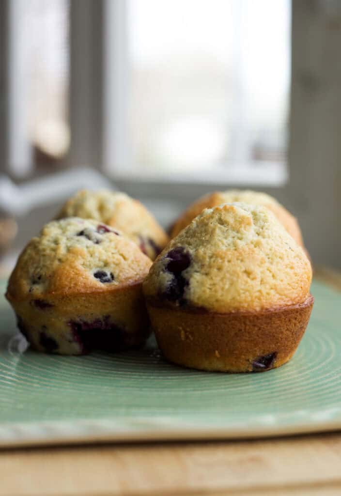 Bakery-style blueberry muffins on a serving board.