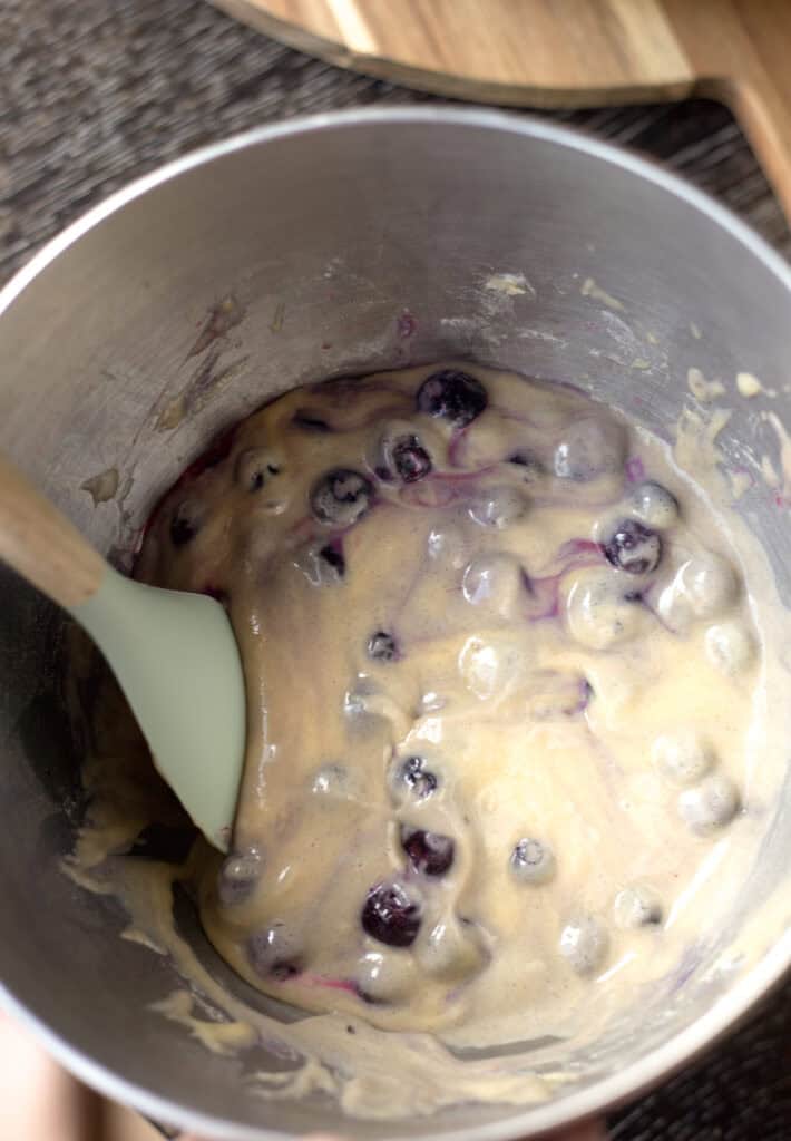 Stirring blueberries into muffin batter.