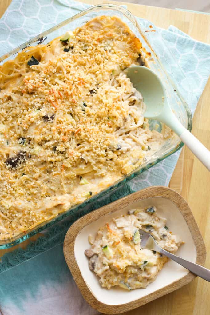 A serving of Million Dollar Chicken Spaghetti next to a casserole dish of it.