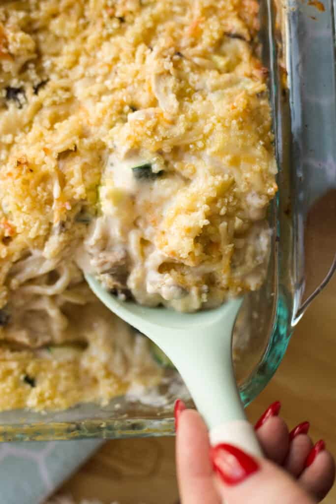 Hand scooping up a portion of Million Dollar Chicken Spaghetti recipe.